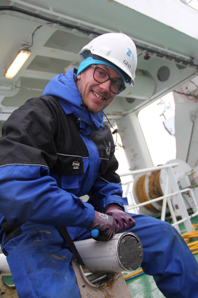 A modeller with clay on his hands! Mads Bruun  Poulsen from NBI cutting a 20 m long sediment core into sections. The  core was taken earlier this week, south of Scoresby Sund, Greenland.  Photo: Ida Synnøve Olsen 